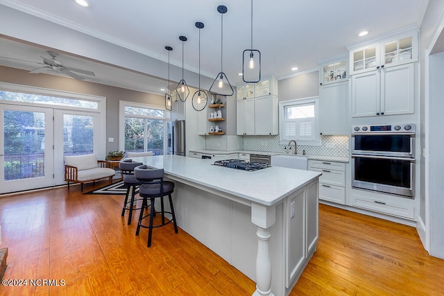 kitchen with white cabinets, a kitchen island, light hardwood / wood-style flooring, decorative light fixtures, and ceiling fan