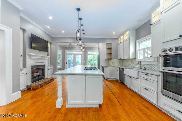 kitchen featuring sink, a kitchen island, a fireplace, light hardwood / wood-style floors, and a healthy amount of sunlight