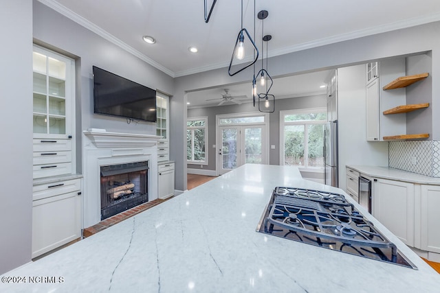 kitchen with light stone counters, white cabinets, pendant lighting, stainless steel appliances, and french doors