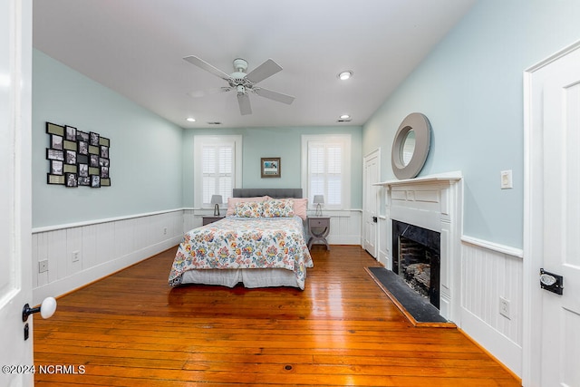 bedroom with ceiling fan, hardwood / wood-style floors, and a high end fireplace