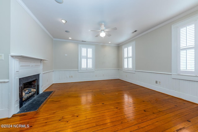 unfurnished living room featuring ceiling fan, a premium fireplace, hardwood / wood-style floors, and crown molding