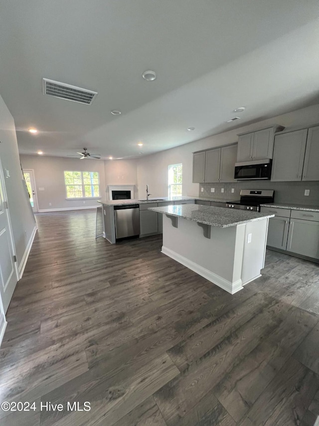 kitchen featuring stainless steel appliances, ceiling fan, dark wood-type flooring, a center island, and gray cabinets