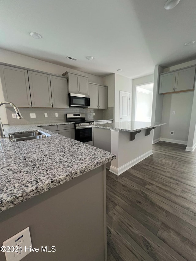 kitchen featuring light stone countertops, sink, stainless steel appliances, dark hardwood / wood-style flooring, and gray cabinets