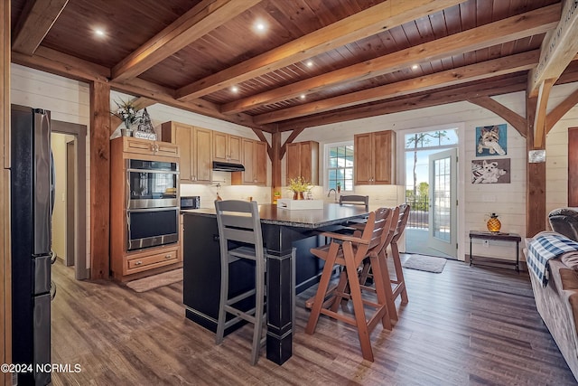 kitchen with a kitchen breakfast bar, a kitchen island, wooden ceiling, black refrigerator, and dark hardwood / wood-style floors