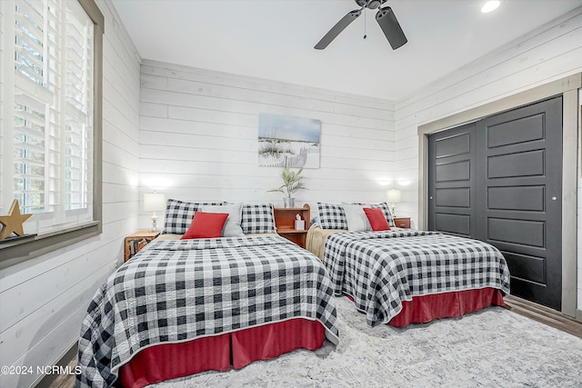 bedroom featuring wooden walls and ceiling fan