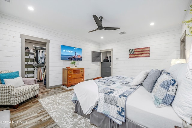 bedroom featuring a closet, wooden walls, wood-type flooring, and ceiling fan