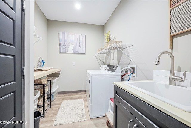 washroom with washing machine and dryer, hookup for a washing machine, sink, and light hardwood / wood-style flooring