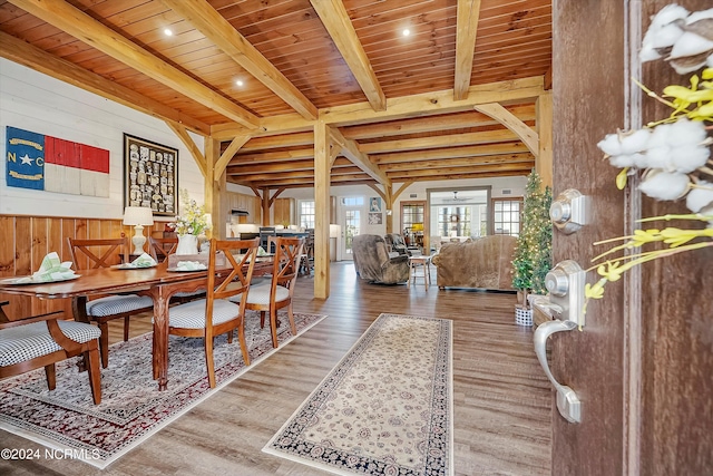 dining area featuring wooden walls, light hardwood / wood-style floors, and beam ceiling