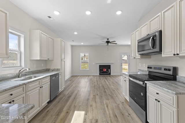 kitchen featuring visible vents, a sink, recessed lighting, appliances with stainless steel finishes, and a fireplace