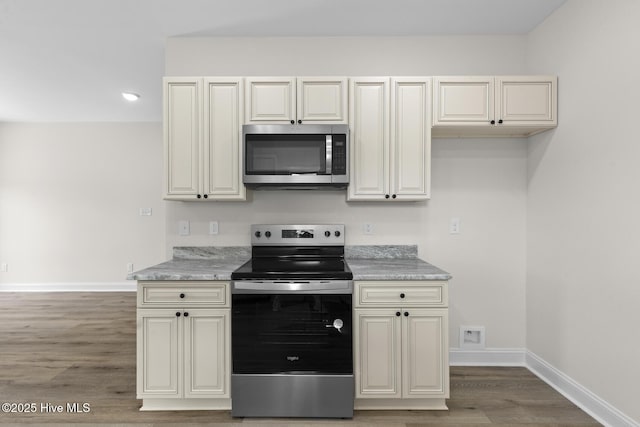 kitchen featuring light wood-style flooring, cream cabinets, baseboards, and stainless steel appliances