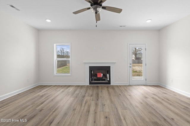 unfurnished living room featuring visible vents, a healthy amount of sunlight, wood finished floors, and a fireplace