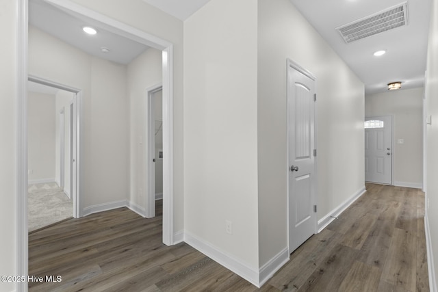 hallway with visible vents, recessed lighting, baseboards, and wood finished floors