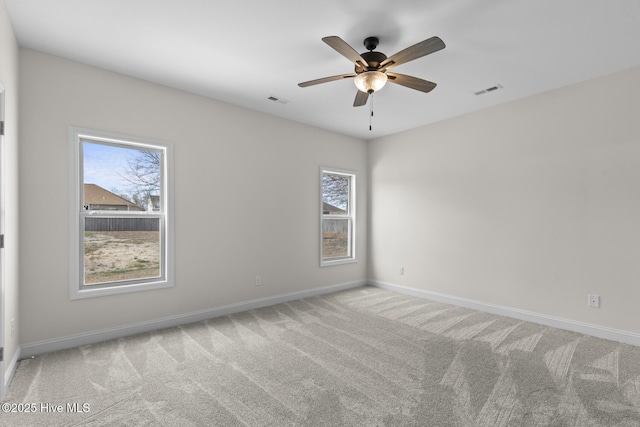 carpeted spare room featuring a ceiling fan, baseboards, and visible vents