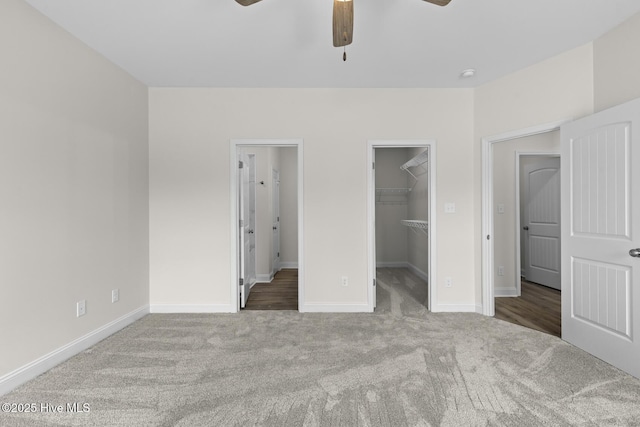 unfurnished bedroom with a spacious closet, carpet, a closet, and baseboards