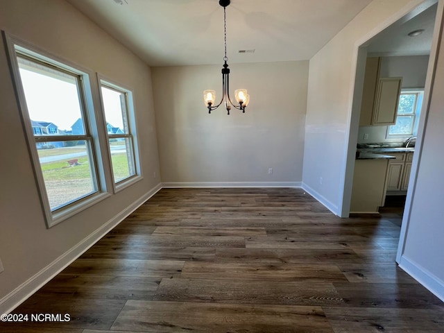 unfurnished dining area with dark hardwood / wood-style flooring, sink, a notable chandelier, and plenty of natural light