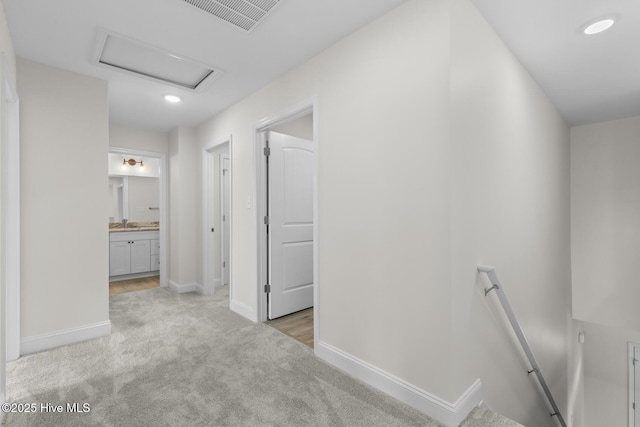 hall featuring visible vents, baseboards, attic access, an upstairs landing, and light colored carpet