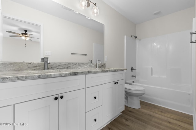 bathroom featuring wood finished floors, shower / washtub combination, toilet, and double vanity