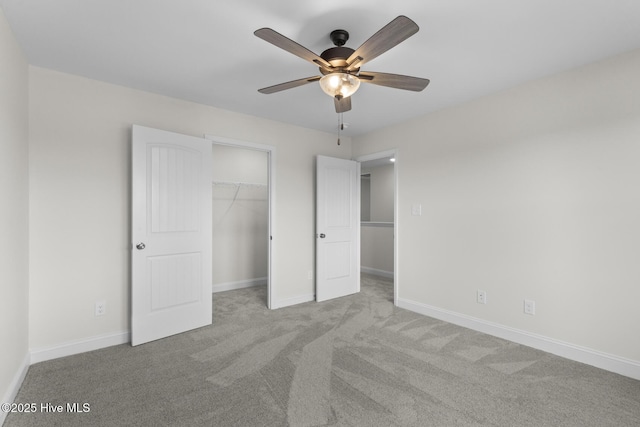 unfurnished bedroom with a closet, a spacious closet, baseboards, and carpet floors