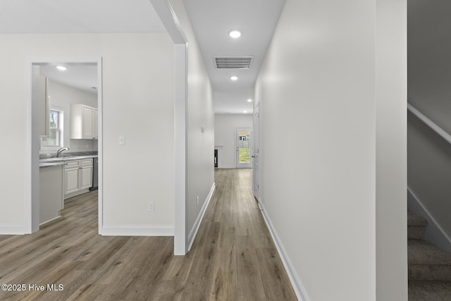 corridor with visible vents, recessed lighting, light wood finished floors, baseboards, and stairs