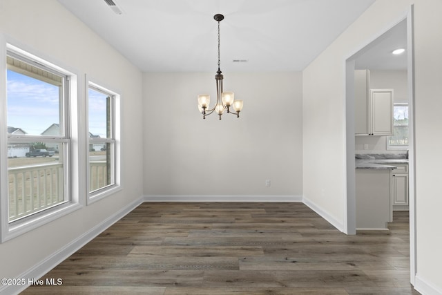 unfurnished dining area with dark wood-type flooring, plenty of natural light, visible vents, and baseboards