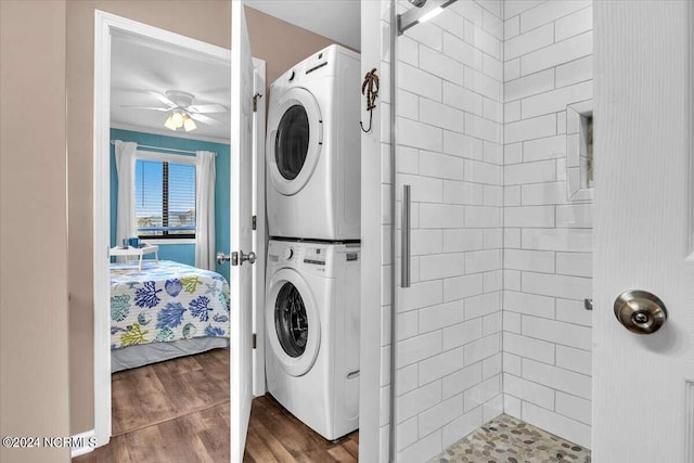 laundry room featuring stacked washer and dryer, wood-type flooring, and ceiling fan