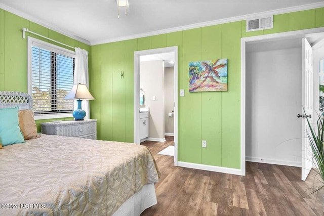 bedroom featuring crown molding, ensuite bath, and dark hardwood / wood-style floors