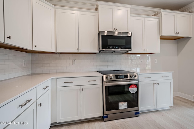 kitchen with backsplash, white cabinetry, light hardwood / wood-style flooring, and appliances with stainless steel finishes