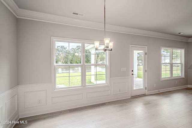 unfurnished dining area with a chandelier, crown molding, a healthy amount of sunlight, and light wood-type flooring