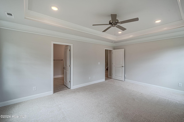 carpeted spare room with a tray ceiling, ceiling fan, and crown molding