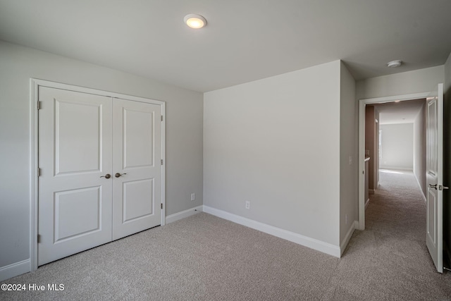 unfurnished bedroom with light carpet and a closet