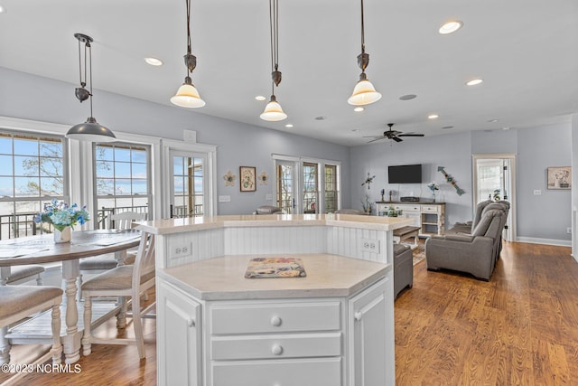 kitchen with light hardwood / wood-style floors, hanging light fixtures, ceiling fan, and white cabinetry