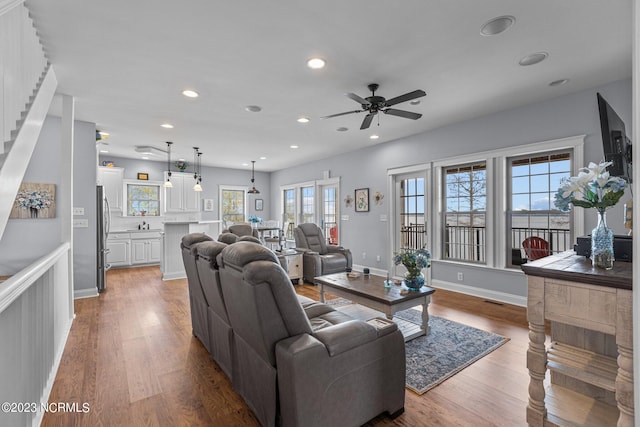 living room featuring light hardwood / wood-style floors, ceiling fan, and a wealth of natural light