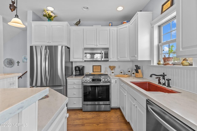 kitchen with white cabinetry, dark hardwood / wood-style floors, appliances with stainless steel finishes, sink, and pendant lighting