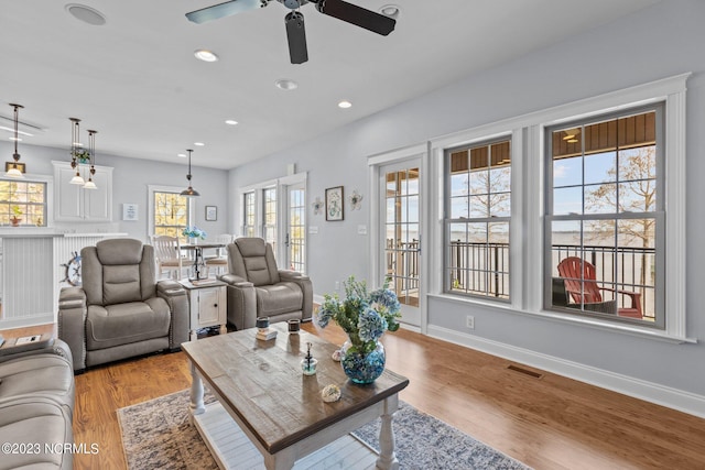 living room with plenty of natural light, french doors, ceiling fan, and light wood-type flooring