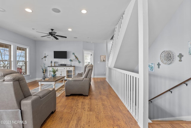 living room with light hardwood / wood-style flooring, ceiling fan, and a healthy amount of sunlight