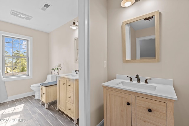 bathroom with dual vanity and toilet