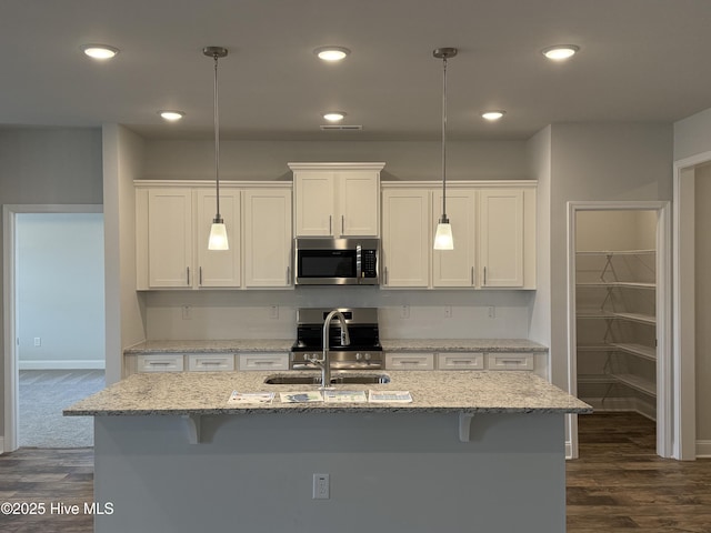 kitchen featuring stainless steel microwave, decorative light fixtures, and white cabinetry