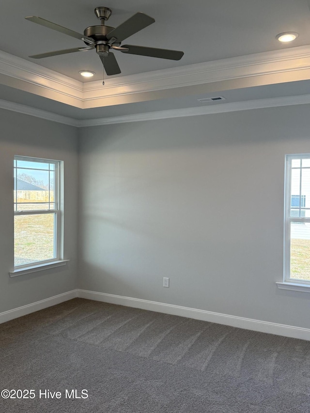 carpeted empty room featuring ornamental molding, a raised ceiling, visible vents, and baseboards