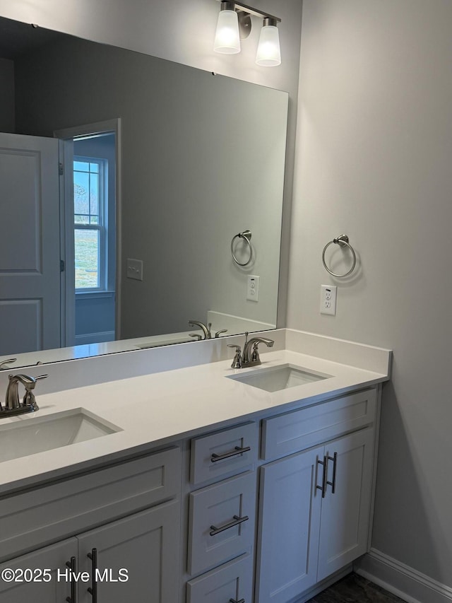 bathroom with double vanity, a sink, and baseboards