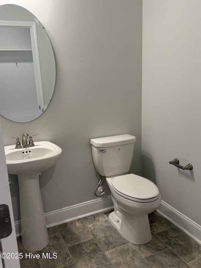 bathroom featuring toilet, baseboards, and a sink