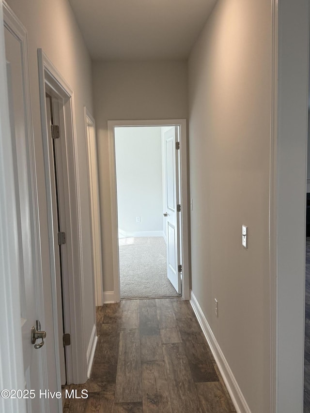 corridor featuring dark wood-style flooring and baseboards