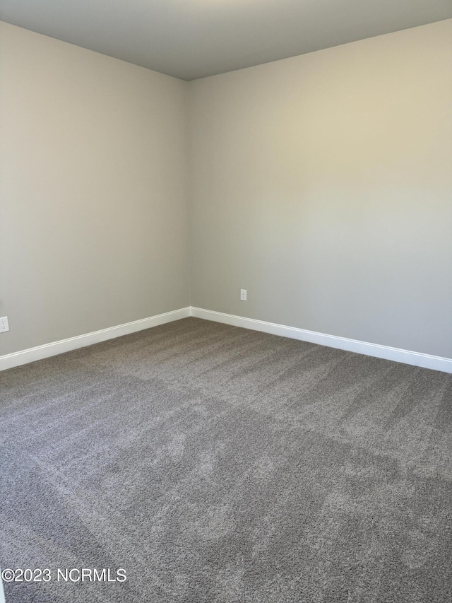 empty room featuring carpet and baseboards