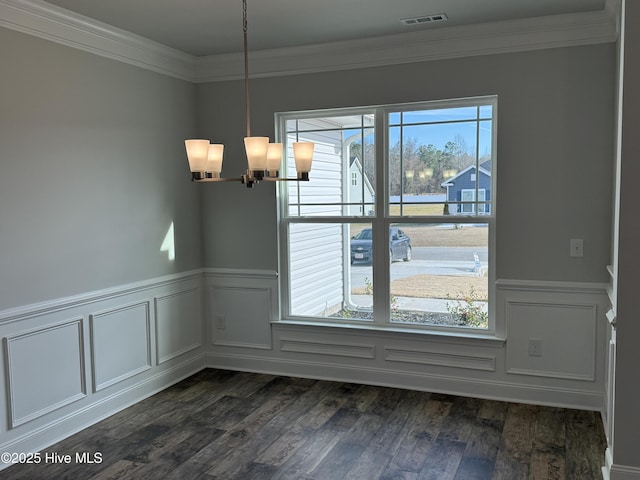 unfurnished dining area with a wainscoted wall, a notable chandelier, visible vents, dark wood-type flooring, and ornamental molding