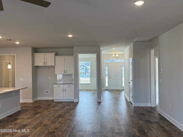 kitchen with light stone counters, white cabinets, and dark wood-style flooring