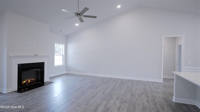 unfurnished living room with a glass covered fireplace, baseboards, and wood finished floors