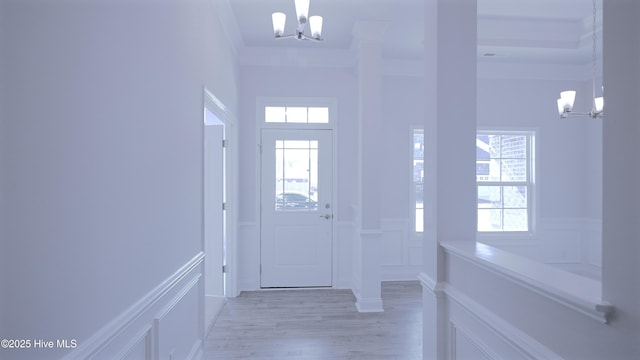 foyer featuring a decorative wall, a healthy amount of sunlight, light wood-style floors, and an inviting chandelier