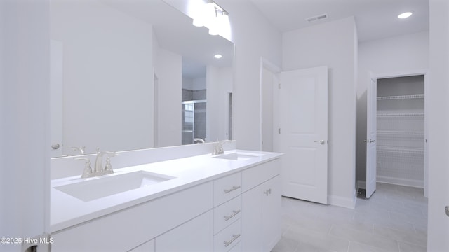 bathroom with double vanity, a stall shower, a sink, and visible vents