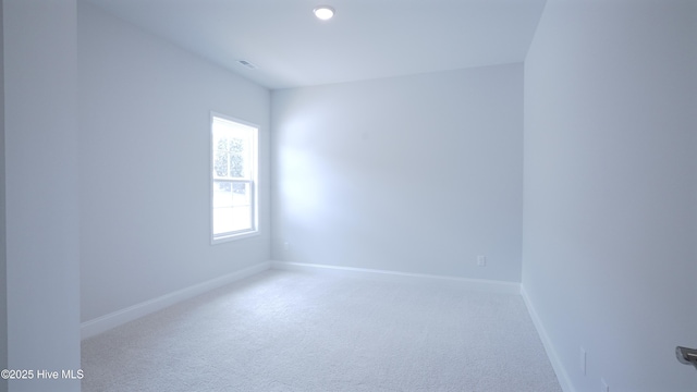 unfurnished room with carpet, visible vents, and baseboards