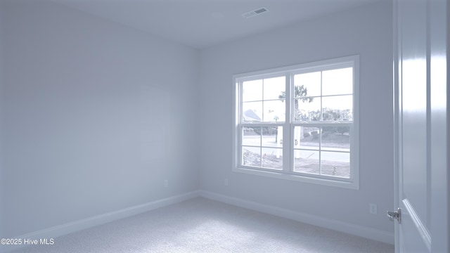 empty room with carpet, visible vents, and baseboards