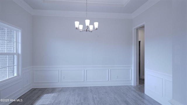 unfurnished dining area featuring ornamental molding, wood finished floors, and an inviting chandelier